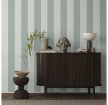 Decoratieve objecten op een dressoir tegen een gestreepte muur.