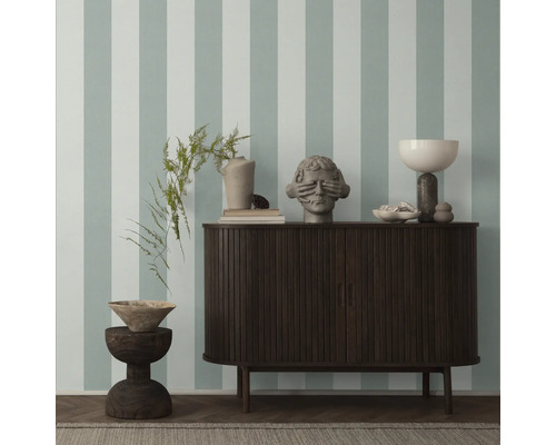 Decoratieve objecten op een dressoir tegen een gestreepte muur.