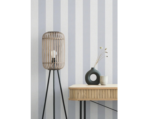 Decoratieve scène met een houten vloerlamp, een dressoir en vazen tegen een gestreept behang.