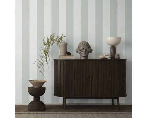 Interieur met een donkerhouten kast, decoratieve elementen en gestreept behang.