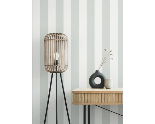 Vloerlamp van bamboe met drie poten en tafel met decoratie voor een gestreepte wand