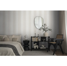 Slaapkamer met bed, plank, fauteuil en gestreept behang