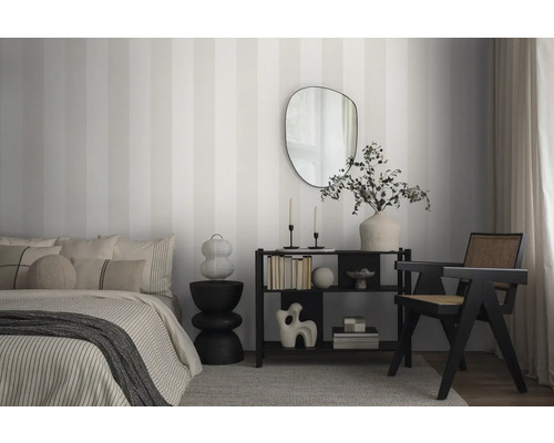 Slaapkamer met bed, plank, fauteuil en gestreept behang