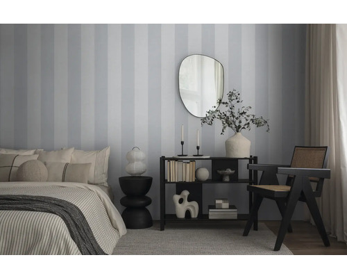 Slaapkamer met bed, commode, spiegel en stoel voor gestreept behang.