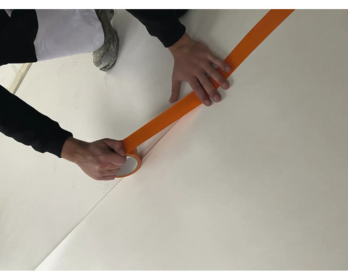 Een persoon plakt afplakband op een vloer om een gebied af te plakken.