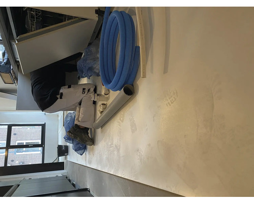 Een vakman installeert een vaatwasser in een keuken.