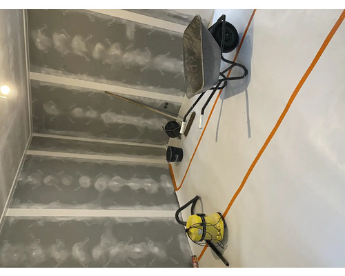 Interieur met gipsplaten, kruiwagen, emmer en tuingereedschap.