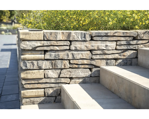 Stenen muur met trap en beplanting in de tuin