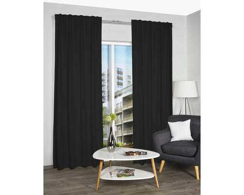 Scene met zwarte gordijnen, een salontafel en een fauteuil in een woonkamer.