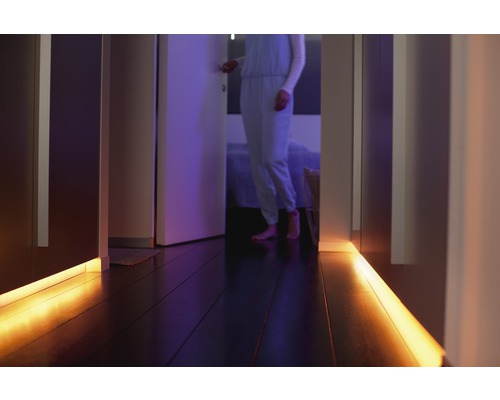Gang met LED-verlichting onder kasten en een persoon op de achtergrond