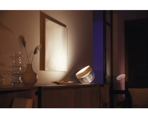 Decoratieve tafellamp op een houten kast met kunstwerk op de achtergrond