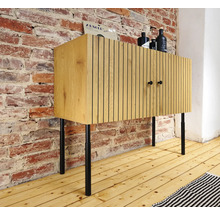 Houten dressoir met twee deuren en zwarte poten voor een bakstenen muur