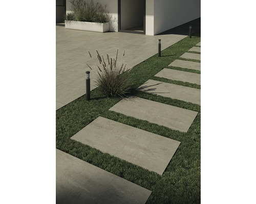 Buitenfoto met stenen platen als voetpad en gazons, gecombineerd met beplanting en buitenverlichting.