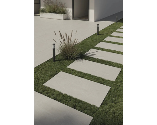 Buitenkant met rechthoekige terrastegels op gras en subtiele buitenverlichting