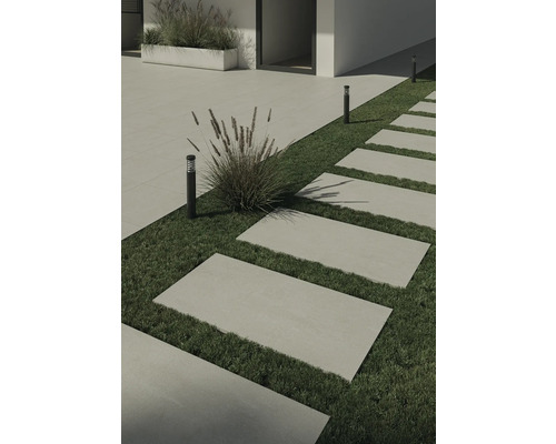 Tuin met stenen loopplaten, gazon en decoratieve lampen