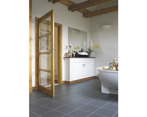 Badkamer met bad, wastafel en houten deur met glazen panelen