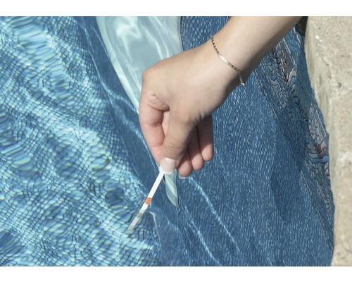 Iemand test het zwembadwater met een teststrip