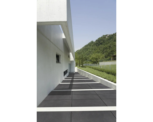 Buitenkant met grijze vloerplaten, een wit gebouw en een groen heuvellandschap