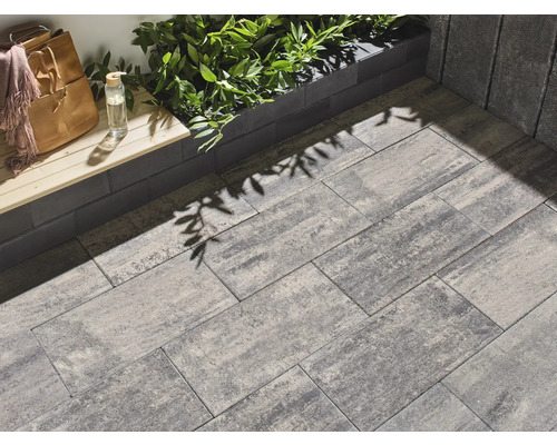 Bestrating van rechthoekige straatstenen in een buitenruimte met decoratieve beplanting