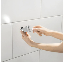 Persoon monteert een handdoekhouder aan een betegelde muur