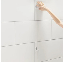 Tegelzetter die wandtegels legt met behulp van een tegelmal