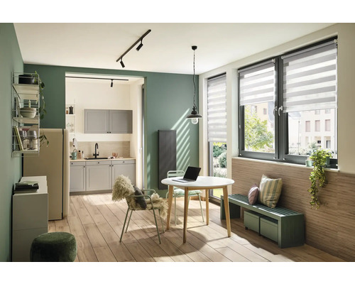 Woonkeuken met eettafel, stoelen, bank en raam met rolgordijn