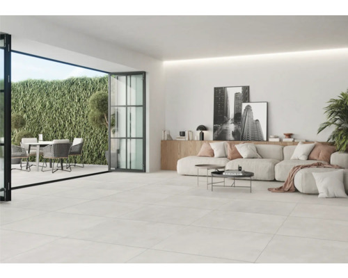 Lichte woonkamer met tegelvloer, terrasdeur en tuinmeubelen