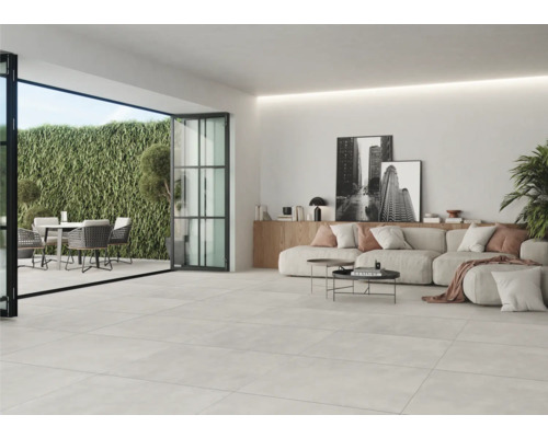 Lichte woonkamer met tegelvloer, zithoek en toegang tot de tuin