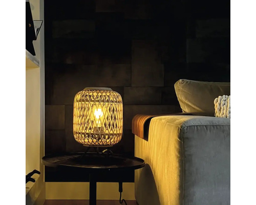 Decoratieve tafellamp van rotan naast een bank op een tafel