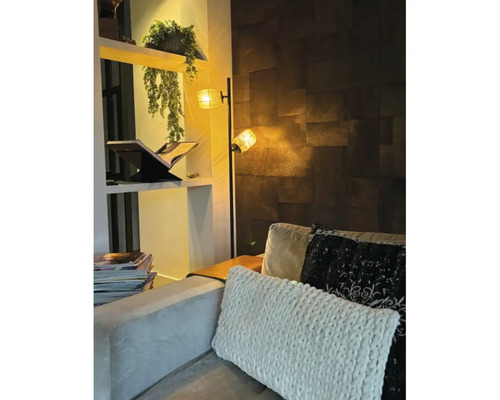 Woonkamer met staande lamp, plank en kussens op de bank.