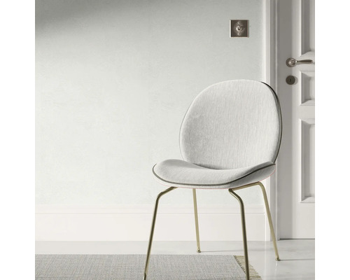 Gestoffeerde stoel met metalen poten voor een muur en een deur