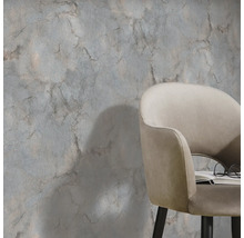 Scene met een wanddecoratie in marmerlook en een fauteuil met boek en bril.