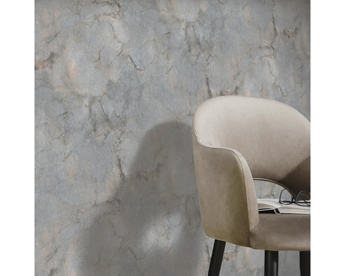 Scene met een wanddecoratie in marmerlook en een fauteuil met boek en bril.