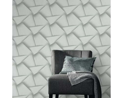 Decoratief behang met driedimensionaal driehoekpatroon en een fauteuil in de kamer.