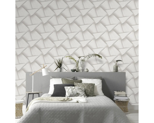 Slaapkamer met bed tegen een muur met driedimensionaal geometrisch behang