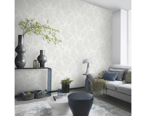 Lichte woonkamer met gedessineerd behang, bank en decoraties.