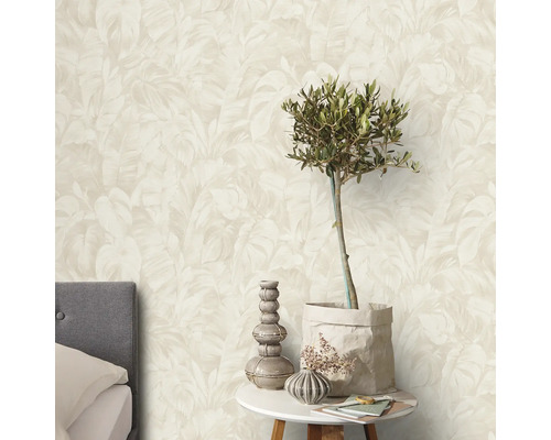 Een slaapkamer met een muur met een behang met bladerenmotief.