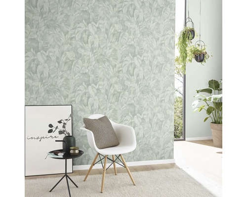 Woonkamer met een wand met een behang met plantenmotief, een stoel en decoratieve elementen.