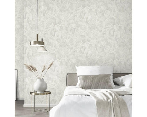 Slaapkamer met bed, nachtkastlamp en behang met bladerpatroon