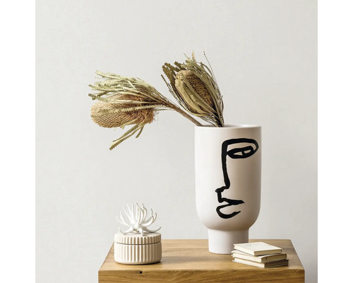 Decoratieve vaas met gezichtspatroon en gedroogde bloemen op een tafel