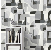 Behang met abstract vormenpatroon in verschillende grijstinten op de achtergrond, rek met decoratieve artikelen op de voorgrond.