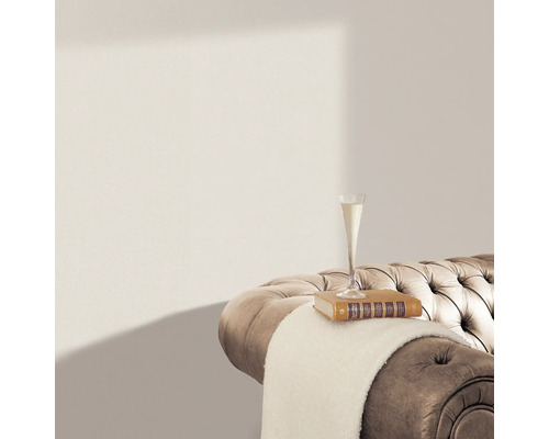 Detailopname van een beige bank met een gecapitonneerd oppervlak, waarop een boek, een lichte deken en een champagneglas staan.