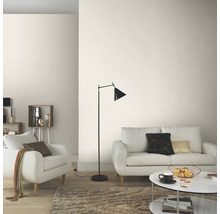 Lichte woonkamer met bank, fauteuil, staande lamp en salontafel