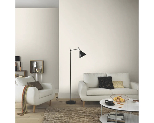 Lichte woonkamer met bank, fauteuil, staande lamp en salontafel