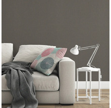 Scene met bank, kussen, deken, bureaulamp en behang met patroon