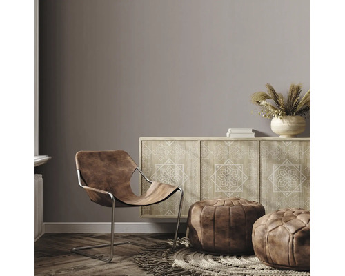 Woonkamer met bruine leren stoel, dressoir met motief en poefs op een vloerkleed