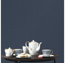 Theeservies en macarons op een tafel voor een blauwe wand