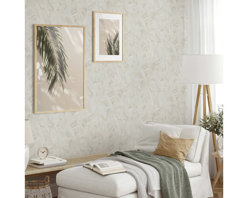 Woonkamer met patroonbehang, twee ingelijste foto''s en witte bank.