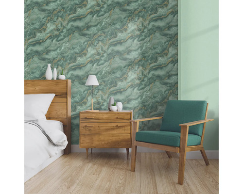 Slaapkamer met bed, nachtkastje en fauteuil voor een muur met marmeren behang.