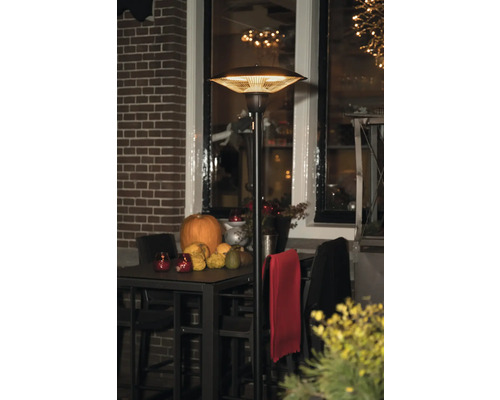 Staande terrasverwarmer naast een tafel met pompoenen en decoraties buitenshuis.